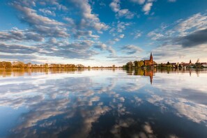 A calm lake reflecting a town with a prominent church and surrounding trees. - Mueritz Landhausperle (Röbel/Müritz)