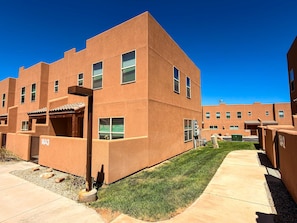 A modern building with a flat roof, multiple windows, and a paved walkway.