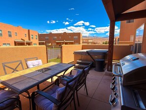 Une terrasse extérieure avec une table et des chaises, un barbecue et une vue sur les bâtiments en arrière-plan.