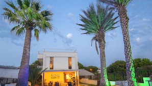 Een modern huis met een zwembad, palmbomen en buitenmeubels.