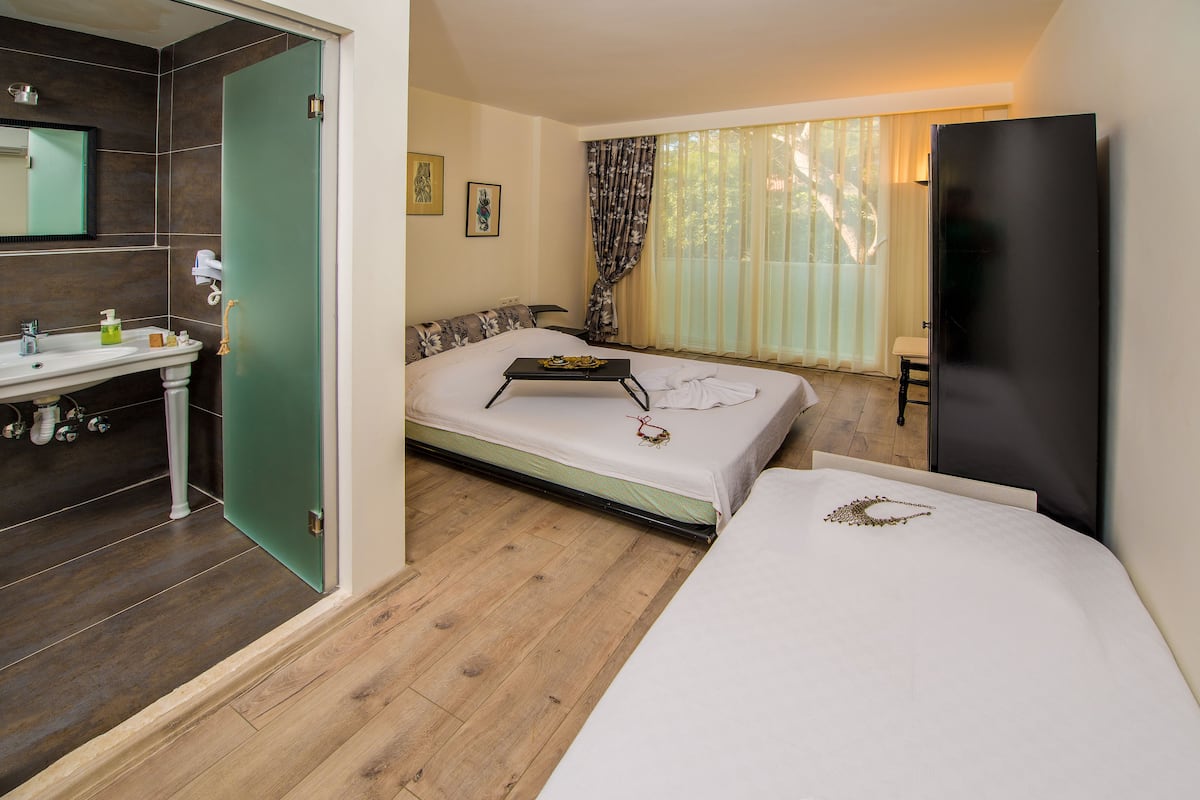 Ein Hotelzimmer mit Bett, Nachttisch und einem Badezimmer mit Waschbecken und Spiegel.