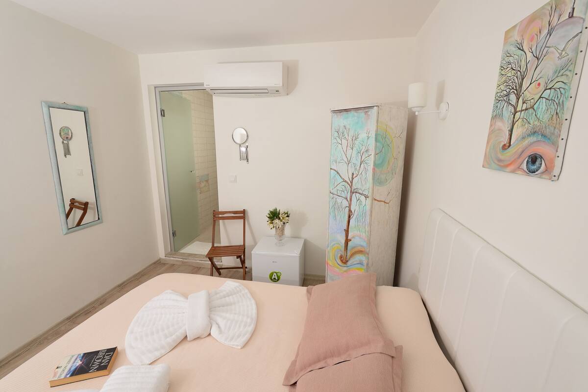 Ein Hotelzimmer mit Bett, Nachttisch mit Lampe, Spiegel und einem Bild an der Wand.