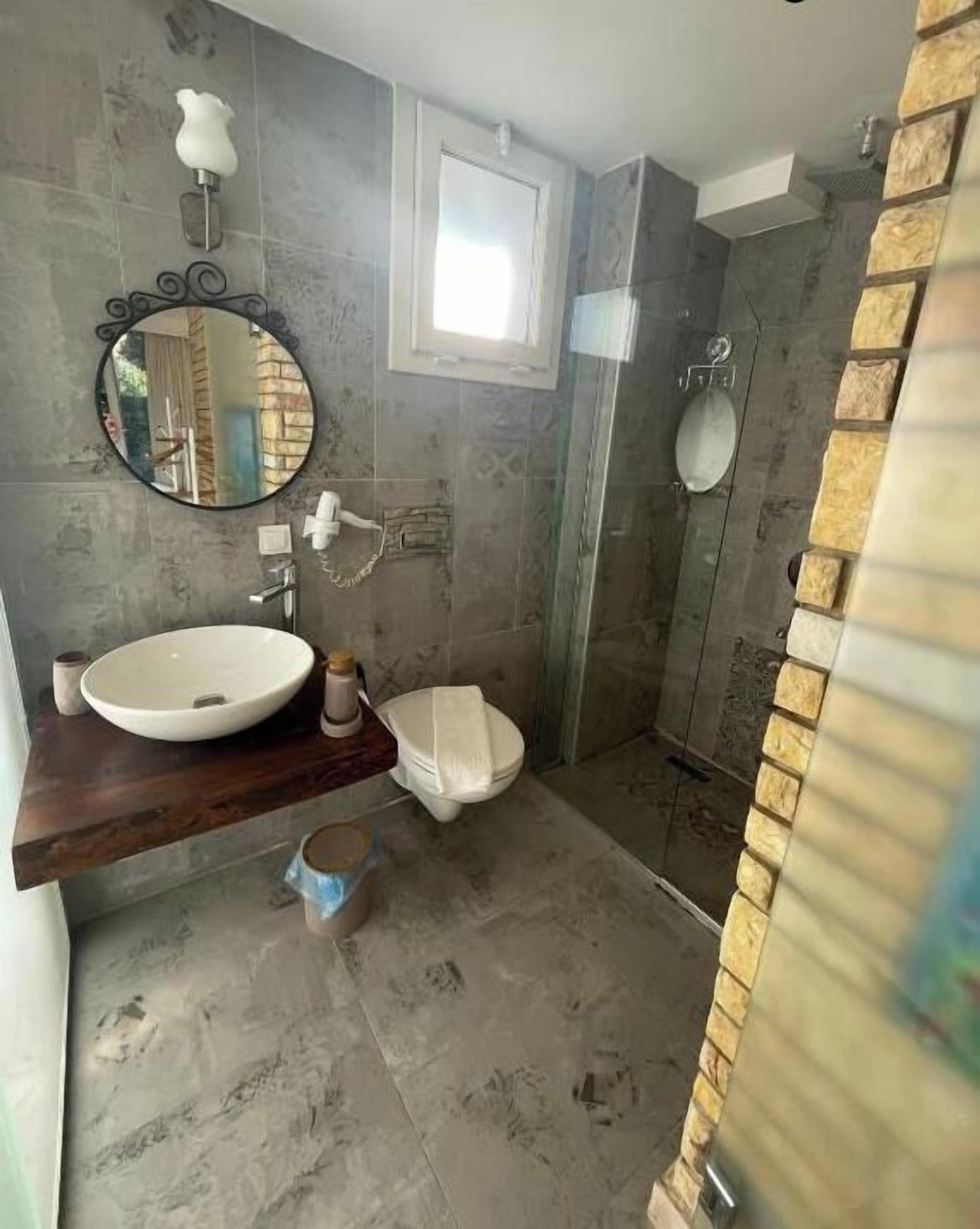 Un baño con un espejo redondo, un lavabo, un inodoro y una zona de ducha.