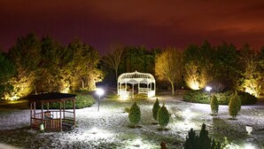 Ein Pavillon mit Dach und Geländern, umgeben von Bäumen und beleuchtet von Straßenlaternen.