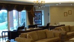 Ein geräumiges Wohnzimmer mit einer großen Sofagarnitur, einem Couchtisch und einem Essbereich mit Stühlen. Es gibt eine Bar mit Regalen voller Flaschen und einem Chandelier.