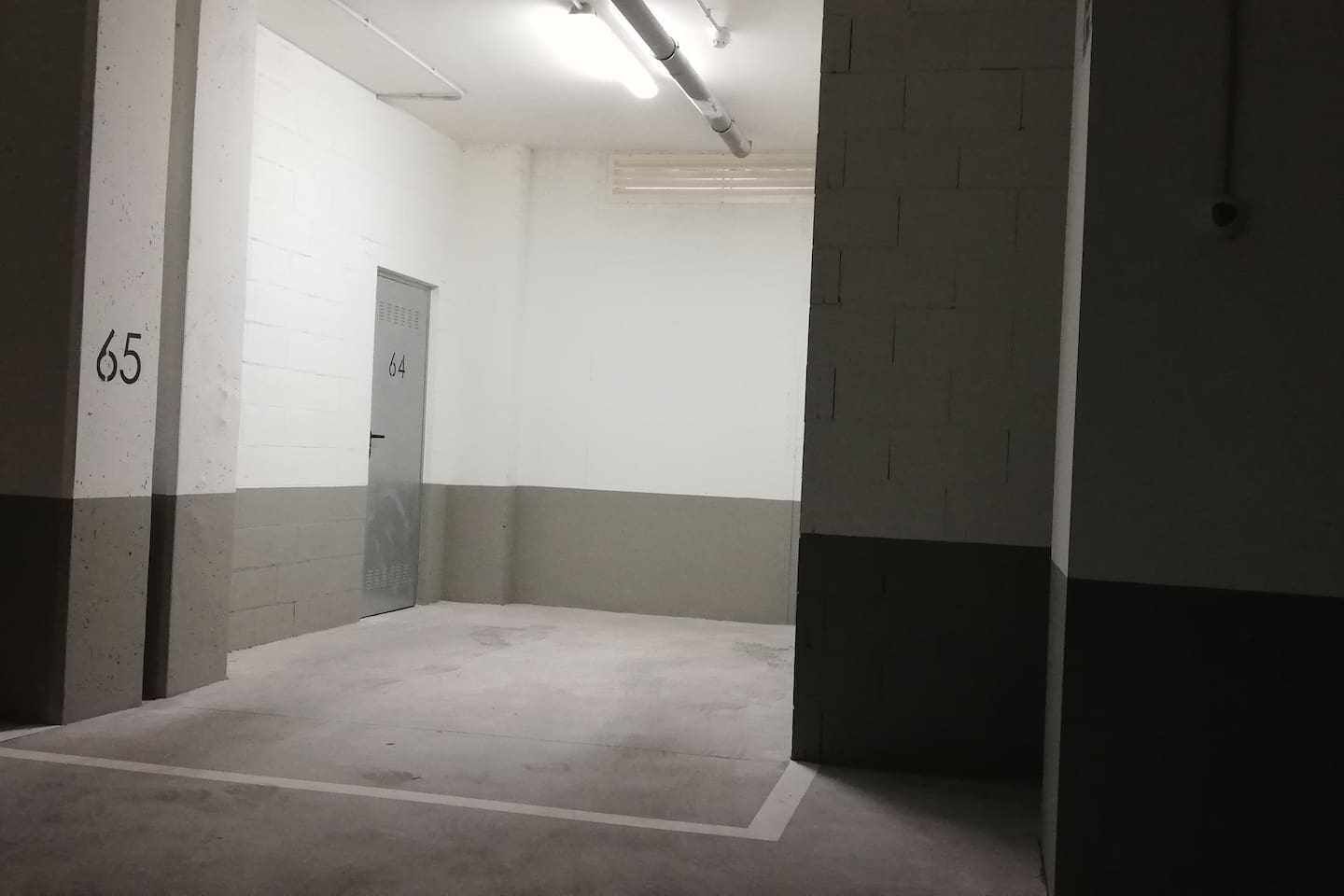 A hallway with a door marked 64, a door marked 65, and a concrete floor.