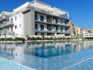 A modern building with a swimming pool in front. - Panorama Beach Apartment - Torrox Costa (Torrox-Costa)