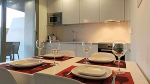 A dining area with a table set for four, equipped with wine glasses and plates, in a modern kitchen with white cabinets and a microwave. - Panorama Beach Apartment - Torrox Costa (Torrox-Costa)