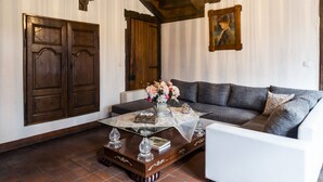 A living room with a sofa, a coffee table with a vase of flowers, and a wooden door. - Rose House B&B (Ghent)