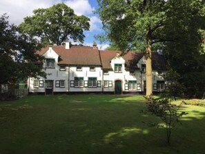 A traditional white building with green accents, a tiled roof, and a well-maintained lawn.