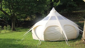 A large, dome-shaped tent with a peaked top, set up on a grassy area surrounded by trees. - Le Moulin Du Luech - Bulles Insolites (Peyremale)