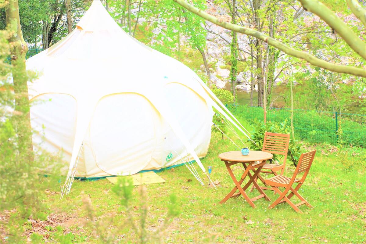 Een tent met een tafel en twee stoelen in een grasveld.