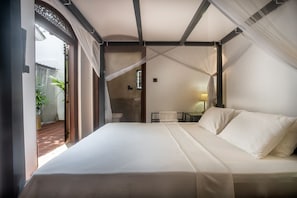 Une chambre avec un grand lit, une table de chevet et une fenêtre avec des rideaux.