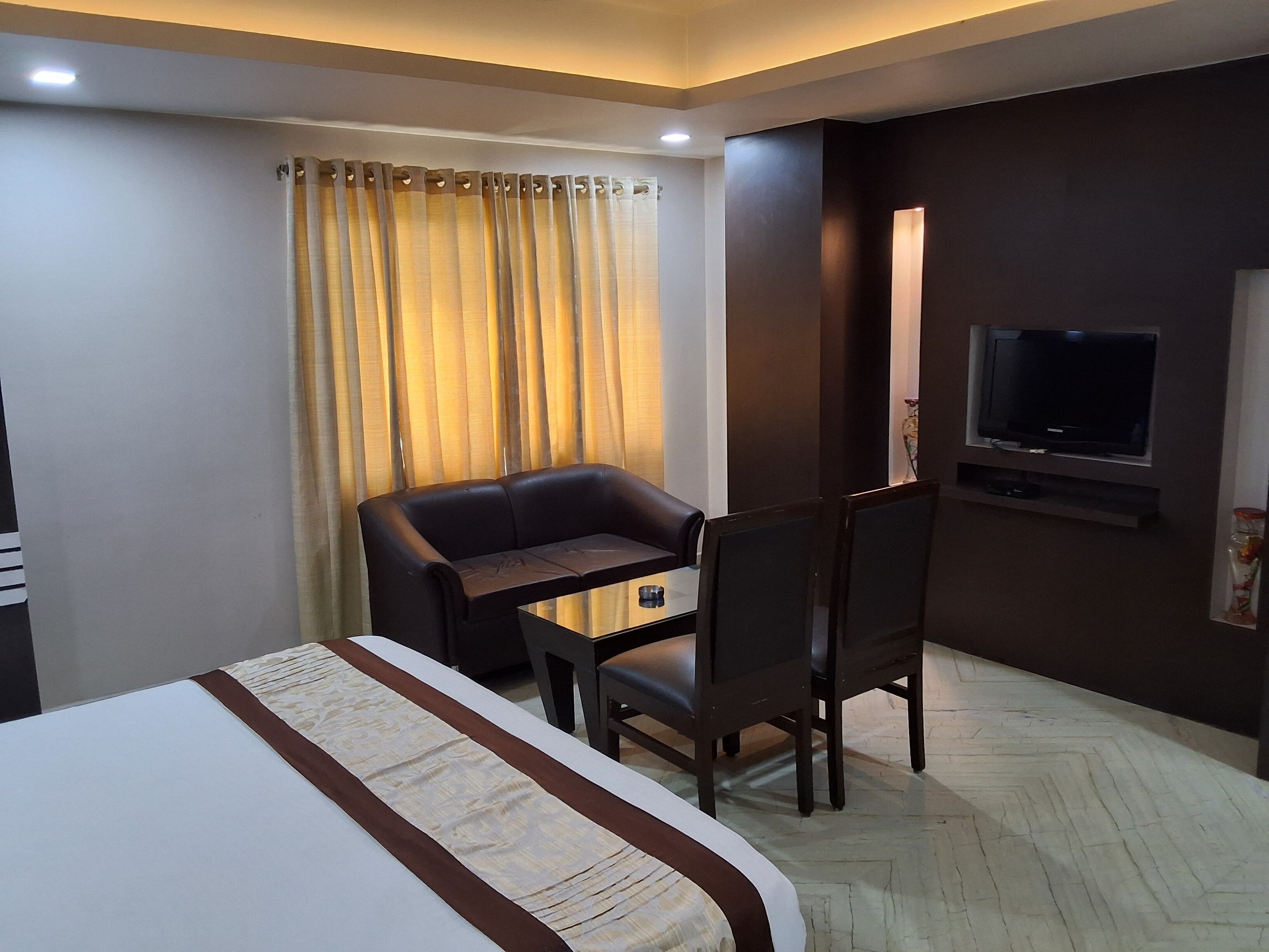 A hotel room with a bed, a desk, a chair, a television, and a curtain.