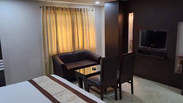A hotel room with a bed, a desk, a chair, a television, and a curtain.