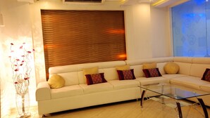A modern living room with a sectional sofa, a glass coffee table, and a decorative floor lamp. - HOTEL ACCORD (Ranchi)