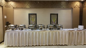 A buffet setup with multiple chafing dishes on a table, surrounded by a white tablecloth. - HOTEL ACCORD (Ranchi)