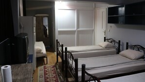 Ein Zimmer mit zwei Einzelbetten, einem Schreibtisch mit Computer und einem an der Wand befestigten Fernseher.