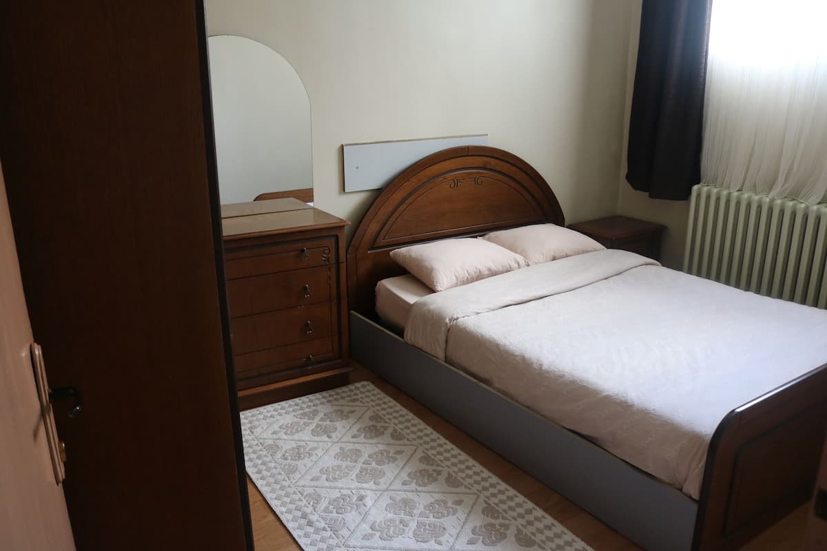 Une chambre à coucher avec un lit, une commode en bois, une table de chevet et un miroir.