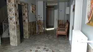 Ein Korridor mit gemusterten Fliesen, einer Treppe, einem Holzstuhl und einem Schild, das einen Salon anzeigt.