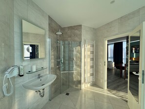 A modern bathroom with a glass shower enclosure, a sink, and a towel rack. - Parkhotel Viktoria (Velten)