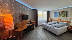 Una habitación de hotel con cama, escritorio, televisor y un cuadro en la pared.
