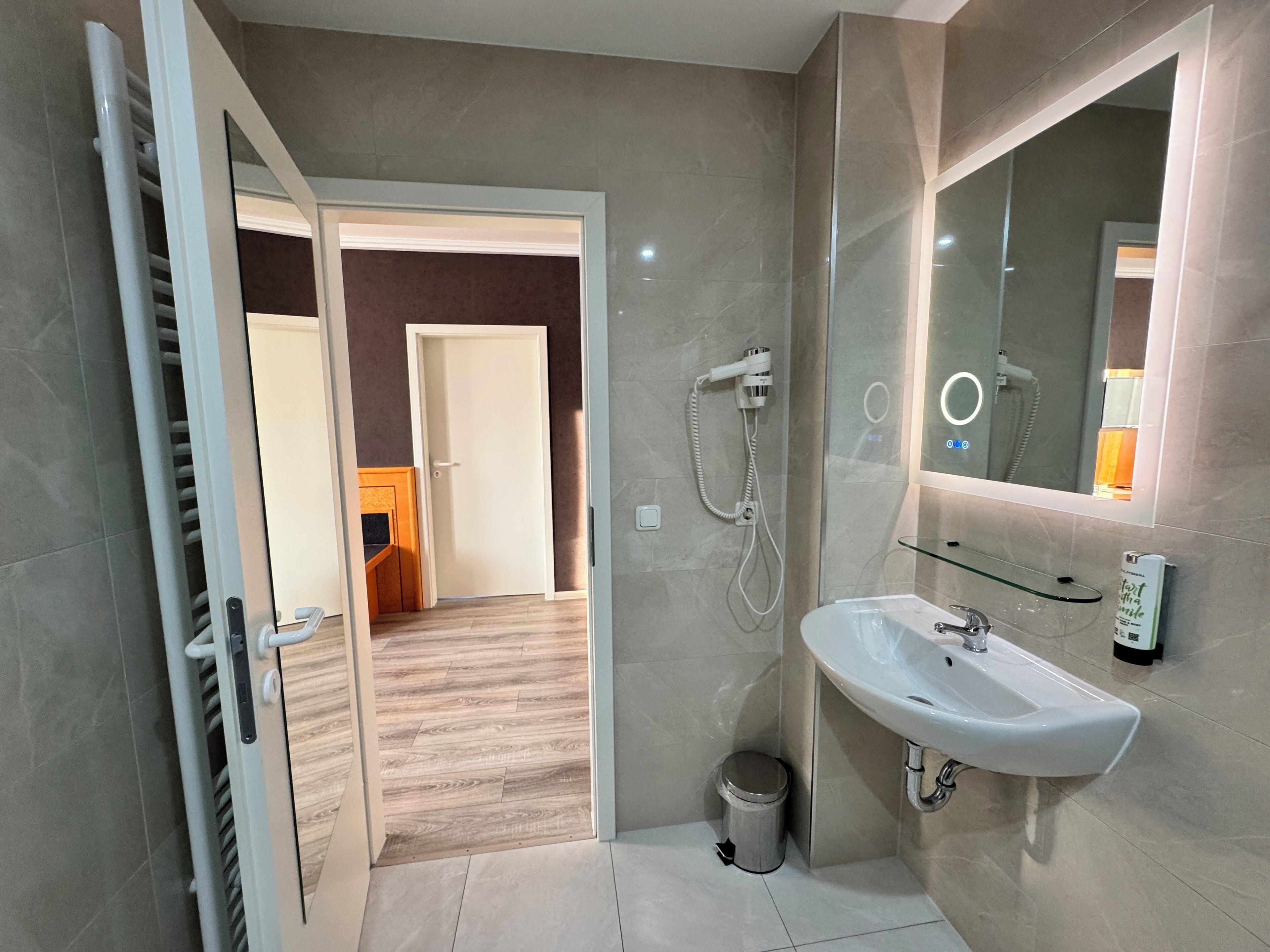 A modern bathroom with a white sink, a glass shower enclosure, and a mirror above the sink.