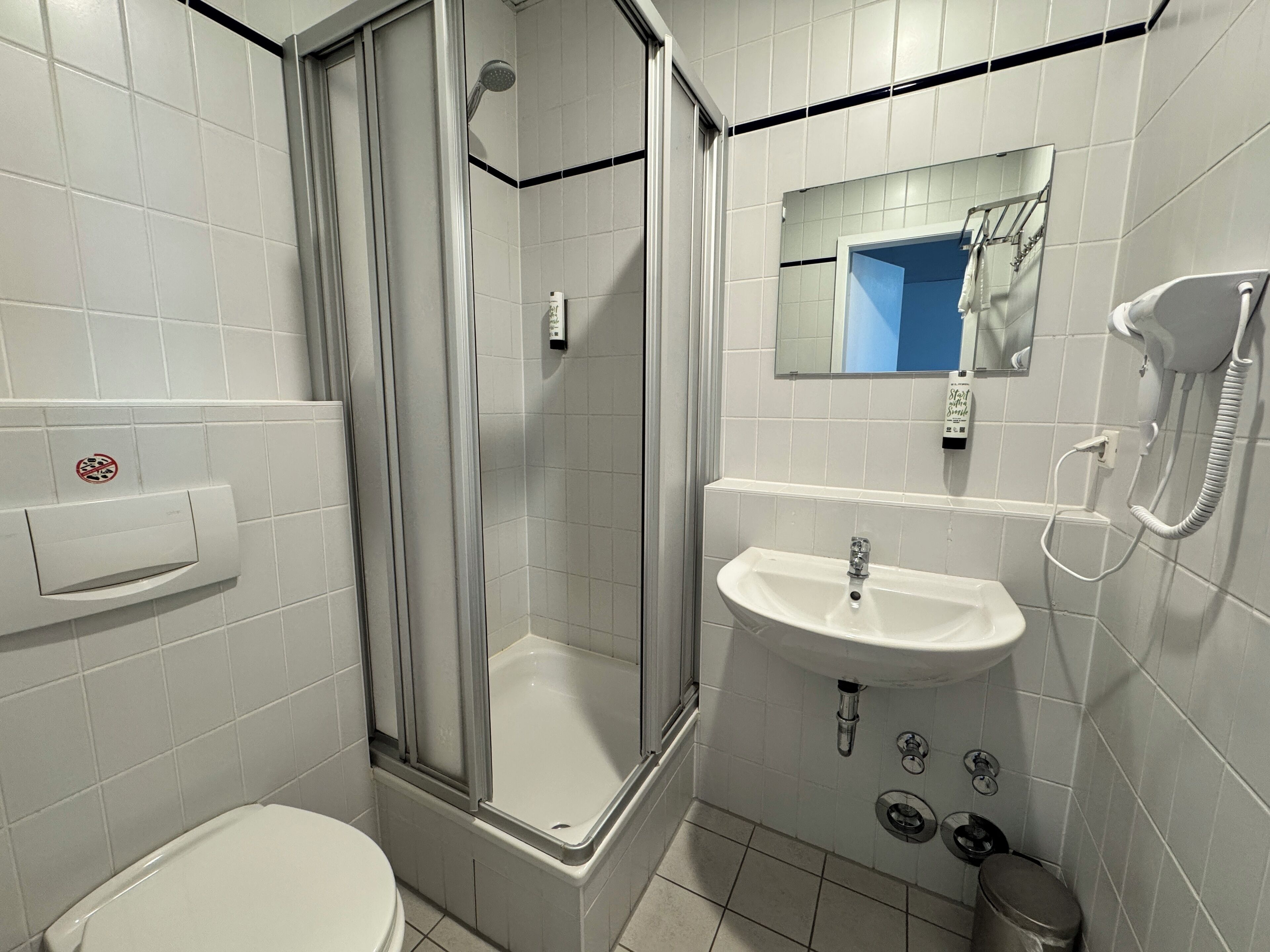 Ein Badezimmer mit Toilette, Dusche, Waschbecken und Telefon.
