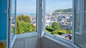 A room with a large window overlooking a town. - Castel de la Terrasse (Etretat)