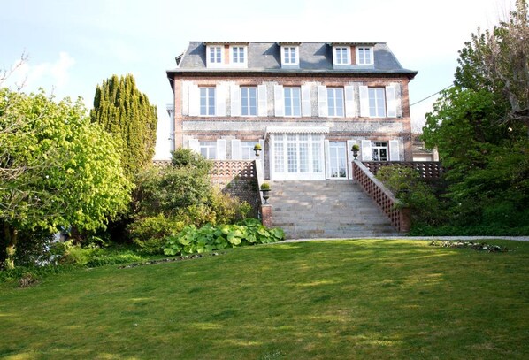 A two-story house with a brick facade, large windows, and a front entrance with steps.