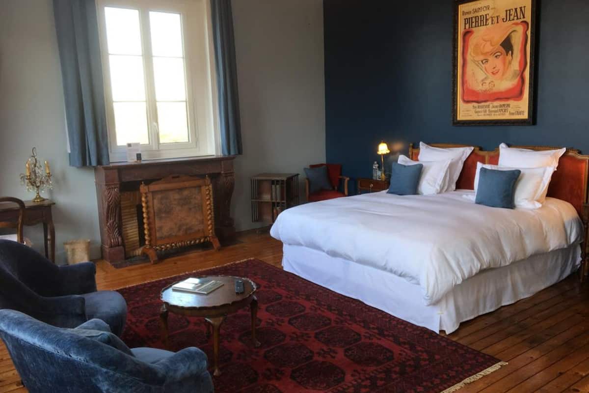 Un dormitorio con una cama grande, una chimenea, un candelabro y un póster en la pared.