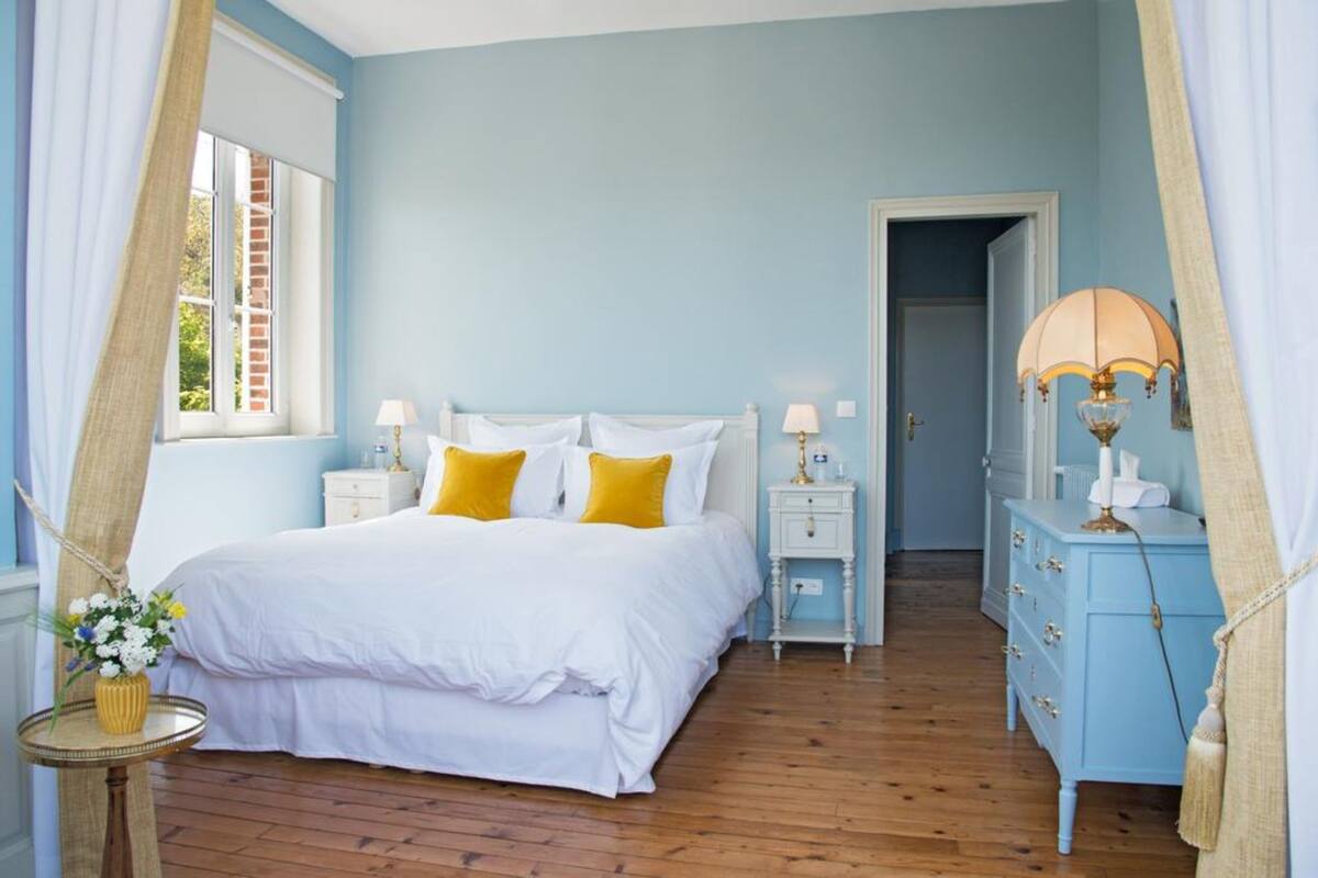 Un dormitorio con cama, mesitas de noche, cómoda y lámpara.