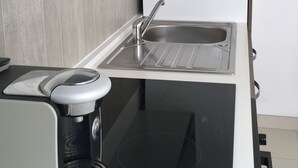 A modern kitchen with a built-in stove, a sink, and a coffee maker. - Furnished apartment T2 St Martin D Héres (Saint-Martin-d'Hères)
