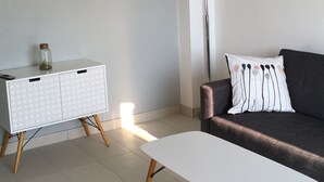 A modern living room with a white cabinet, a dark sofa, and a white coffee table. - Furnished apartment T2 St Martin D Héres (Saint-Martin-d'Hères)