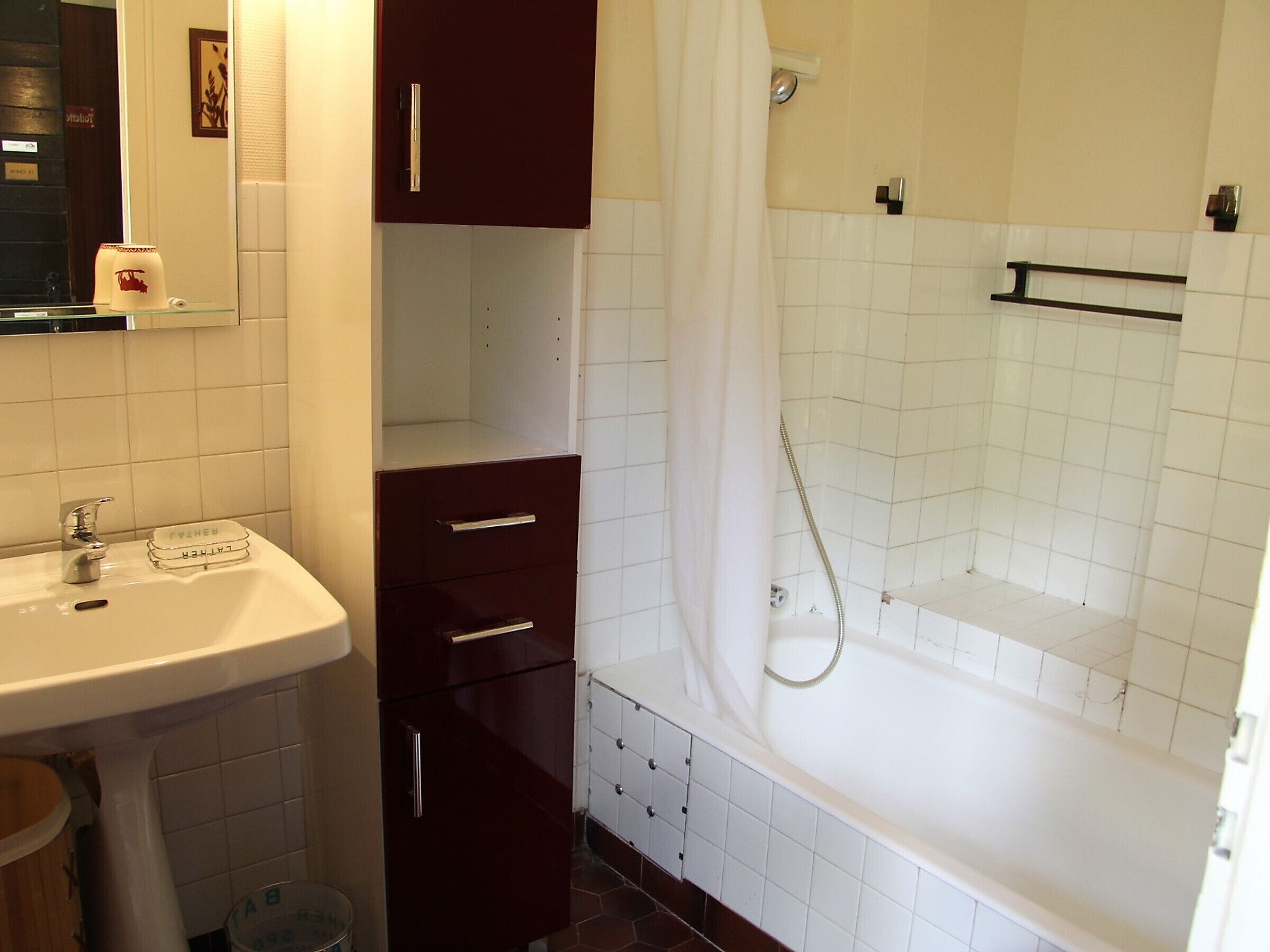 A bathroom with a sink, mirror, cabinet, and bathtub.
