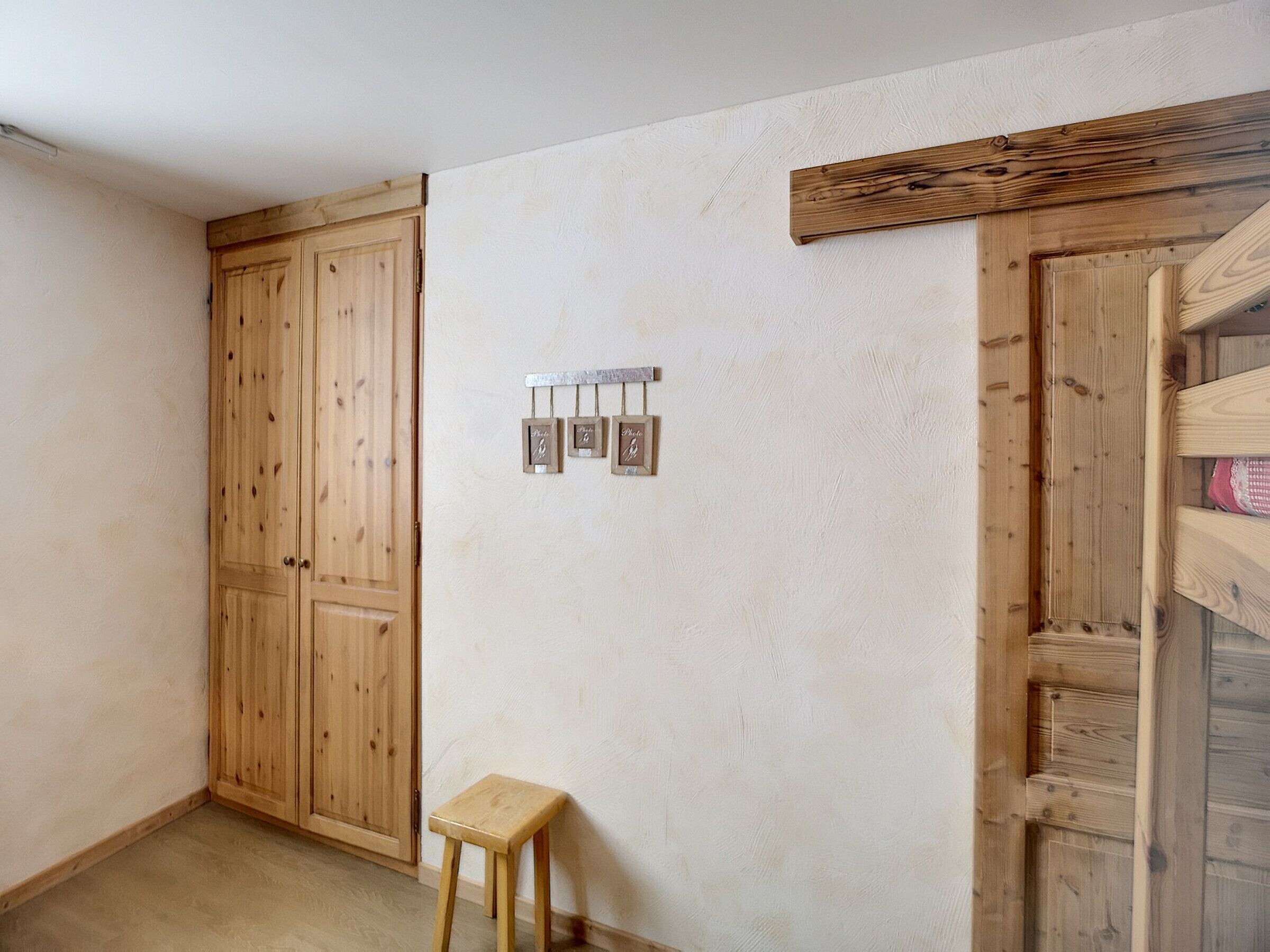 Een kamer met houten kasten, een klein krukje en een lichtschakelaar op de muur.