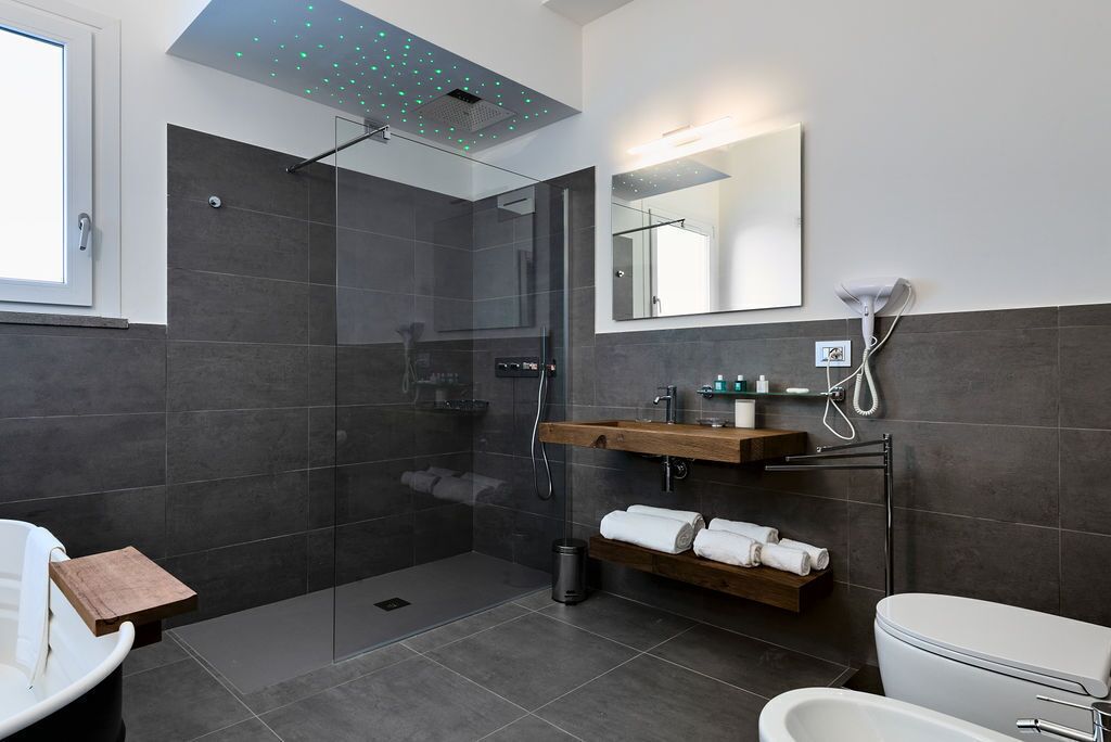 Un baño moderno con ducha de vidrio, tocador de madera, inodoro y un espejo grande.