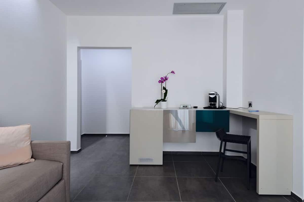A modern, minimalist office space with a desk, chair, and a small potted orchid.
