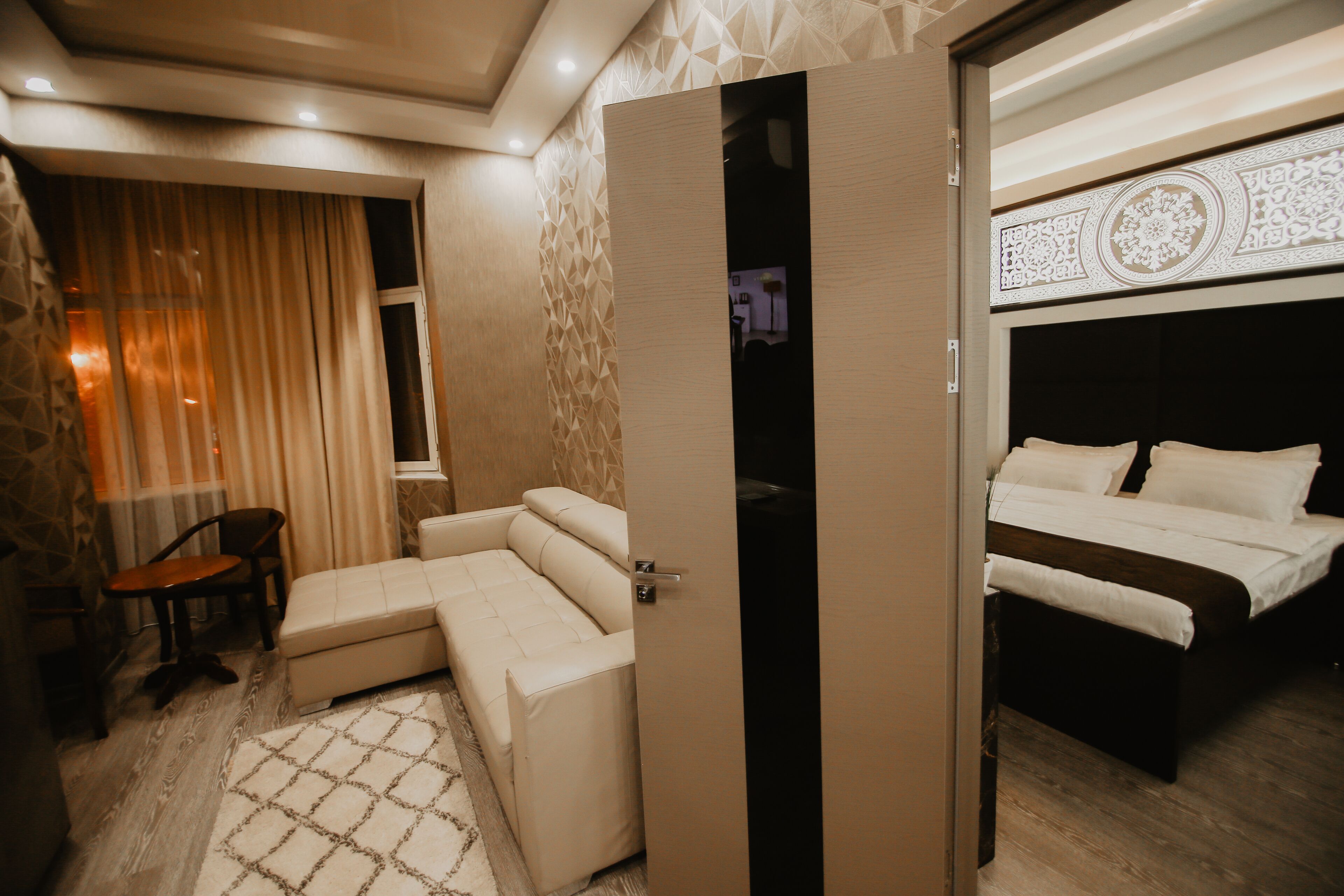 A hotel room with a sofa, a bed, and a partially open door leading to another room.