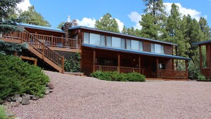 A wooden lodge with a covered porch, a staircase, and a gravel driveway.
