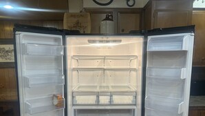 An open refrigerator with multiple shelves and drawers, a milk carton, and a wine bottle.