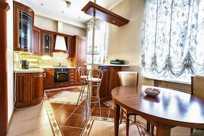 Enjoy meals in the kitchen with an oven and range hood, adjacent to a dining area with a round table and chairs.