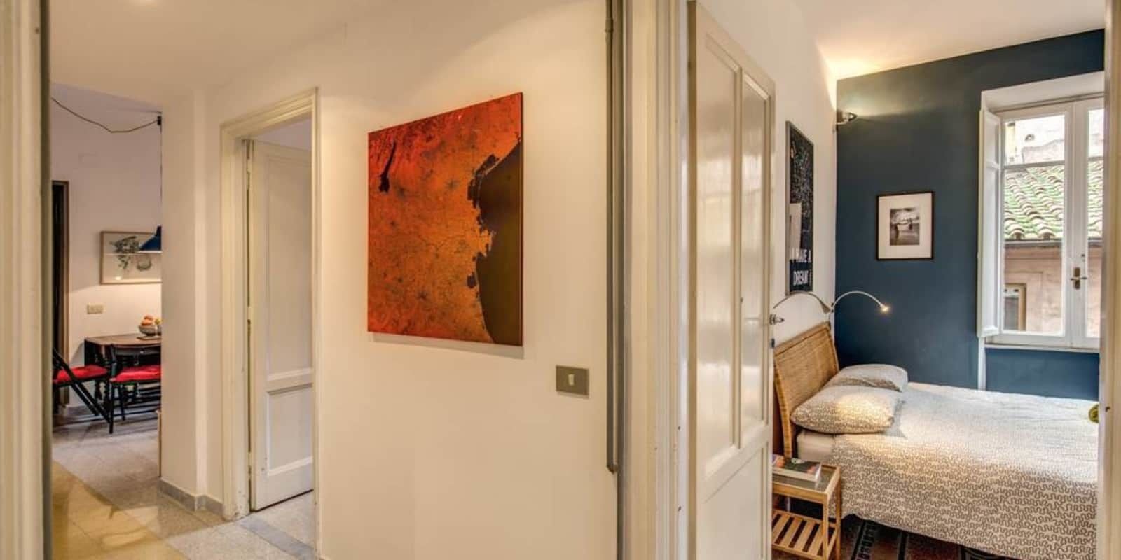 A bedroom with a bed, a window, and a wall-mounted artwork.