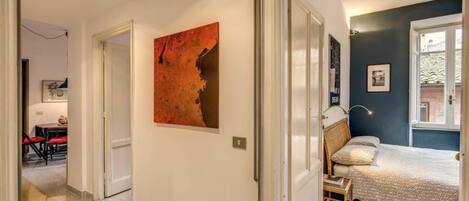 A bedroom with a bed, a window, and a wall-mounted artwork.