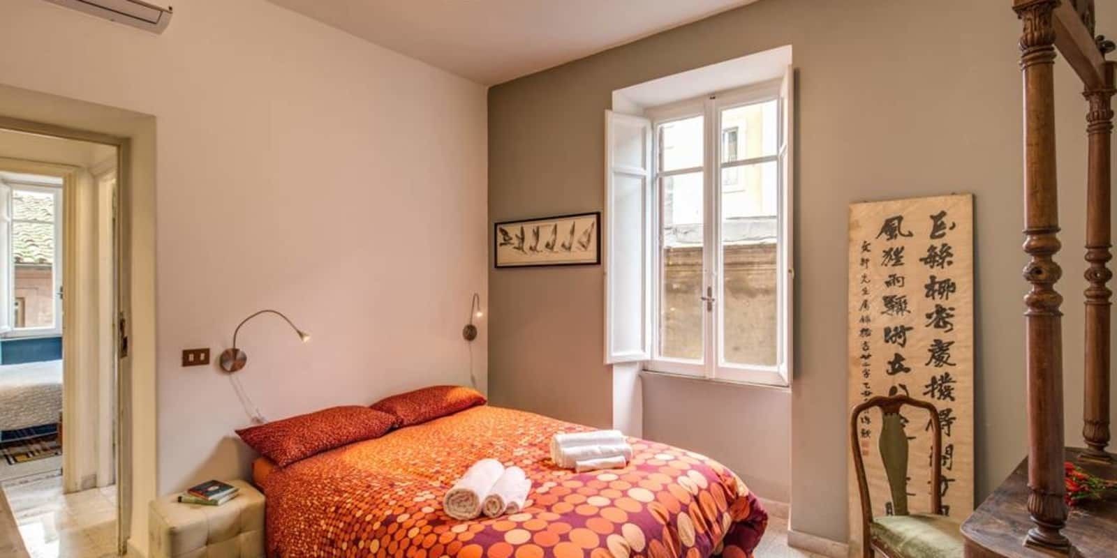 A bedroom with a bed, a window, a chair, and a wall with writing.