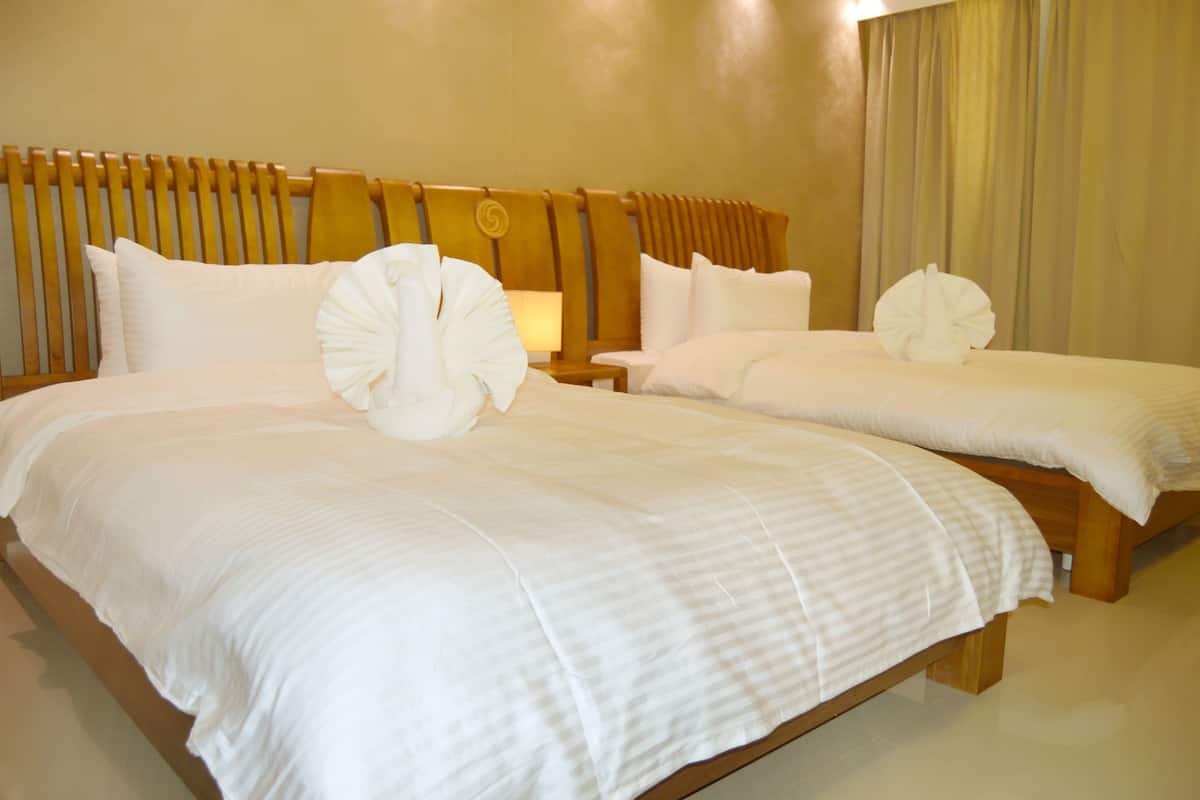 Habitación de hotel con dos camas, cabecero de madera y una lámpara.