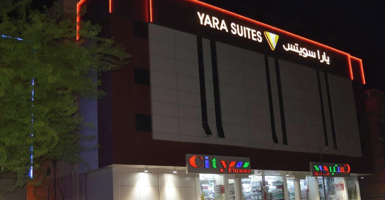 Un edificio con un letrero que dice 'YARA SUITES' y una tienda llamada 'City Flower'.