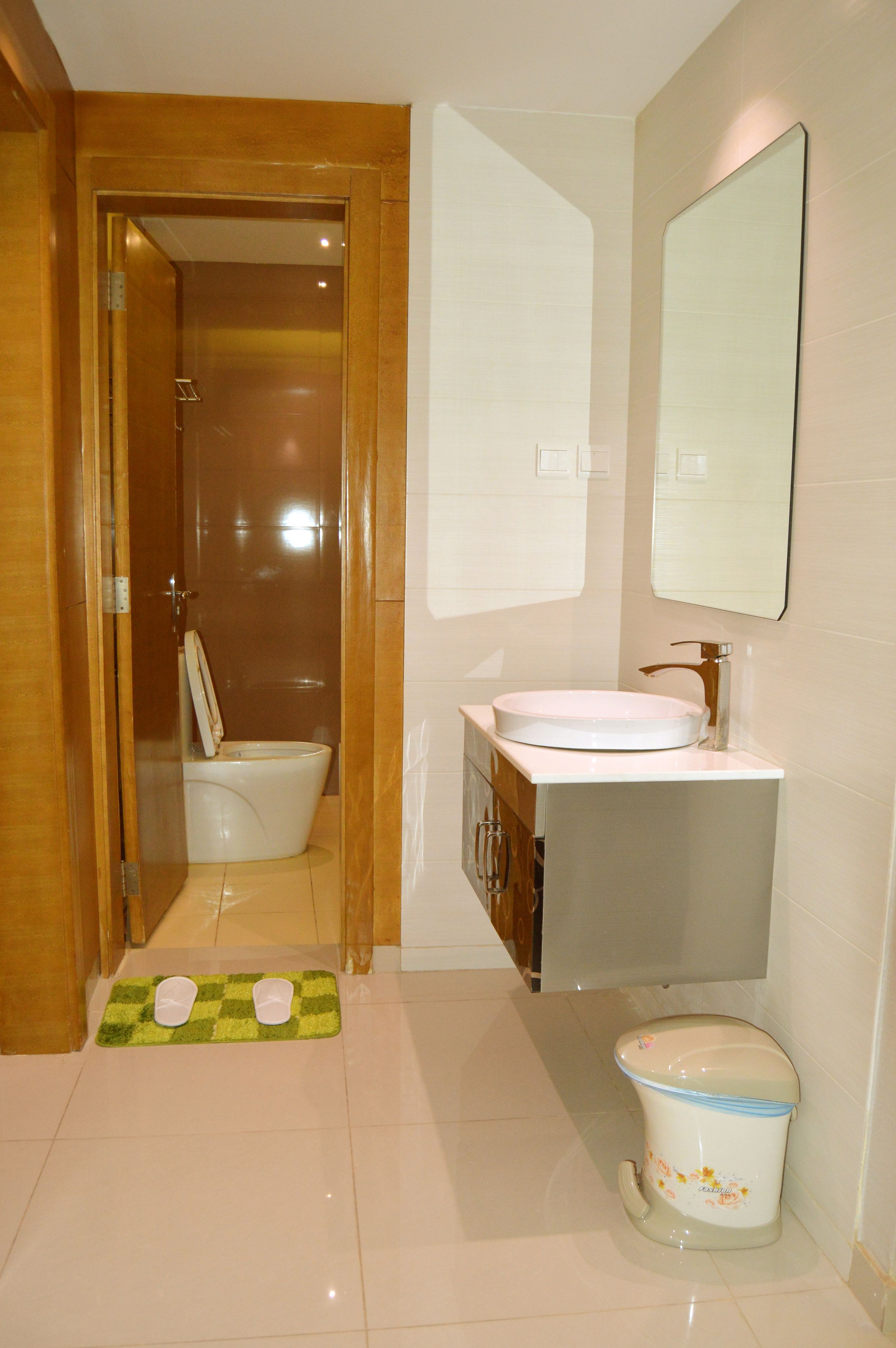 A bathroom with a toilet, sink, and mirror.