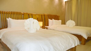Une chambre d’hôtel avec deux lits, chacun agrémenté de draps blancs et d’oreillers décoratifs.