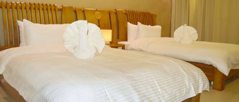 Habitación de hotel con dos camas, cada una con ropa blanca y almohadas decorativas.
